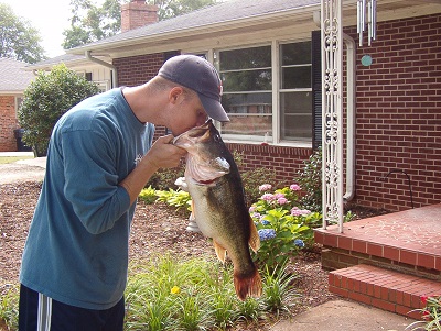 man looking into mouth of largemouth bass