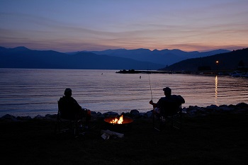 two people fishing at dusk on shoreline