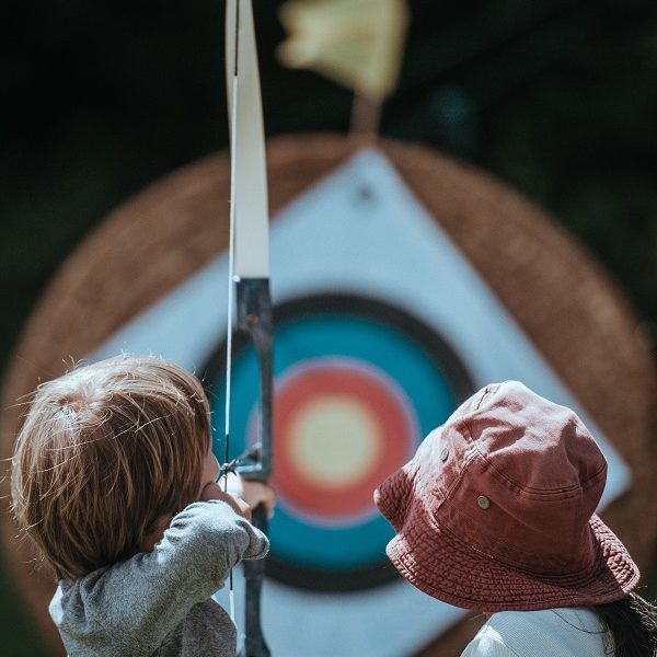 young kids shooting at archery target
