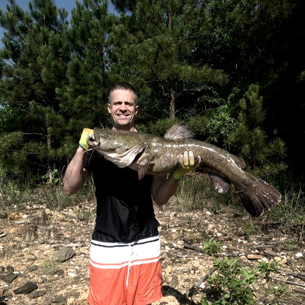 man holding flathead catfish that he caught with bare hands