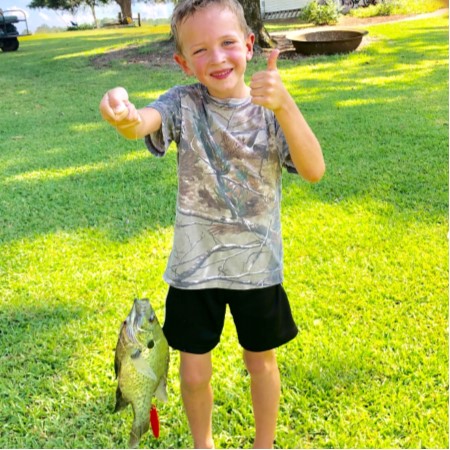 boy holding fish with thumbs up