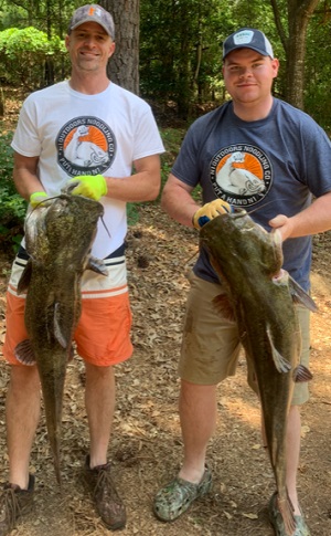 men holding flathead catfish caught noodling