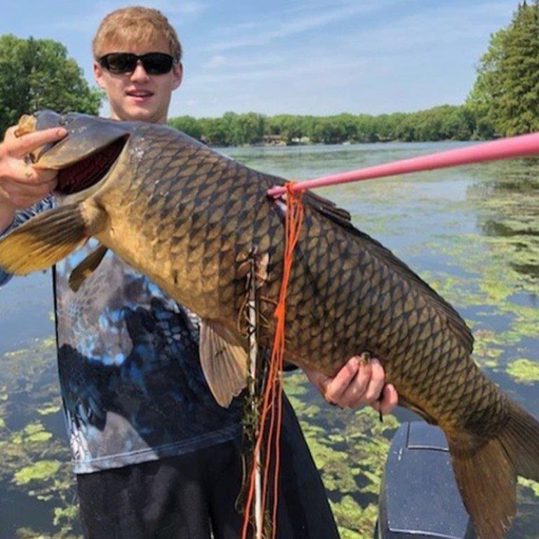 man hold carp with bowfishing arrow stuck in it