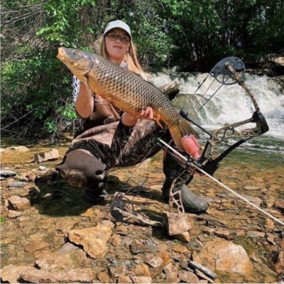 bowfishing woman holding carp with bow