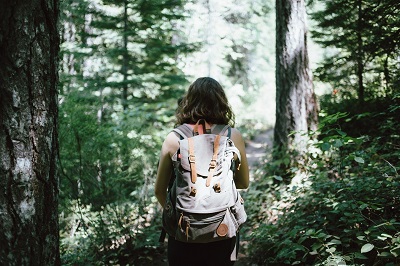 girl with backpack hiking in woods