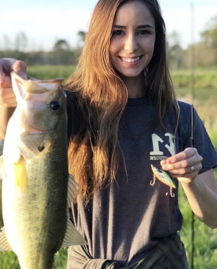 Aly from Alabama holding largemouth bass and wearing N1 Outdoors fishing shirt