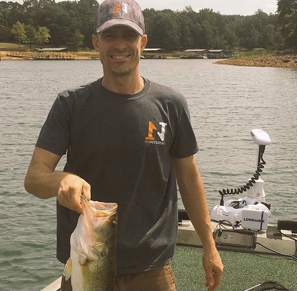 man holding largemouth bass wearing N1 Outdoors fishing shirt