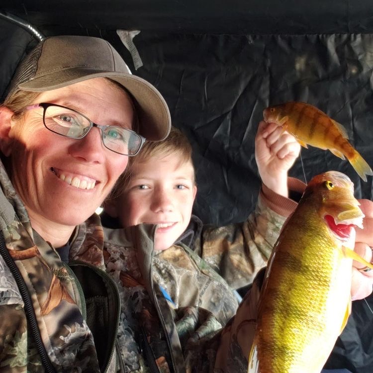 mother and son hold yellow perch while ice fishing