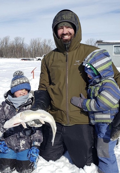 kids ice fishing with dad holding fish