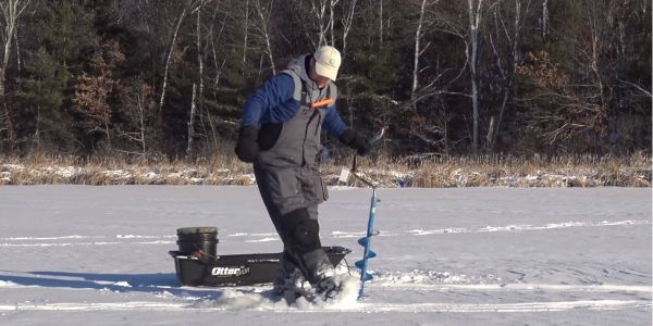 man removing slush from ice fishing hole