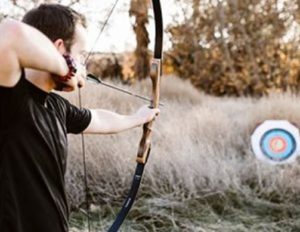 man shooting trad bow at round target