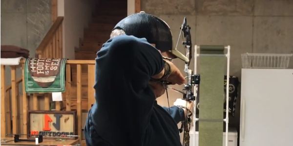 man shooting bow through paper while nock tuning