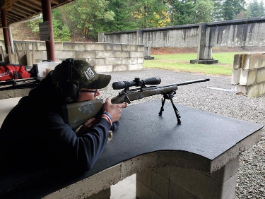 man shooting rifle with scope on range