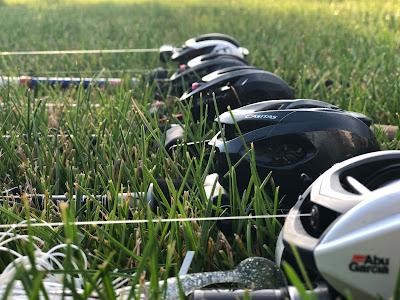 four baitcaster fishing rods lined up in the grass