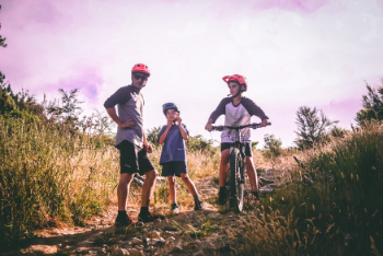 family mountain biking wearing bike helmets