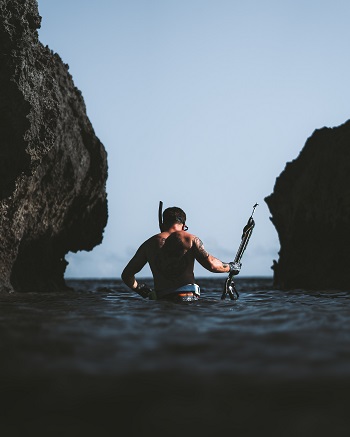 man in shallow water with speargun