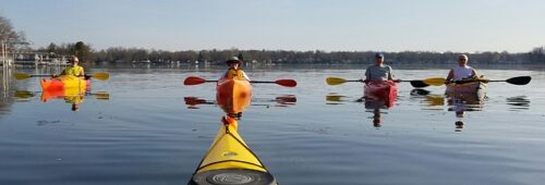 people sitting in calm water in kayaks