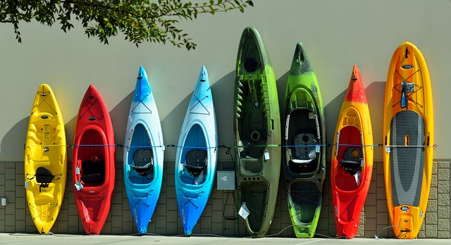 various types of kayaks leaning against a wall