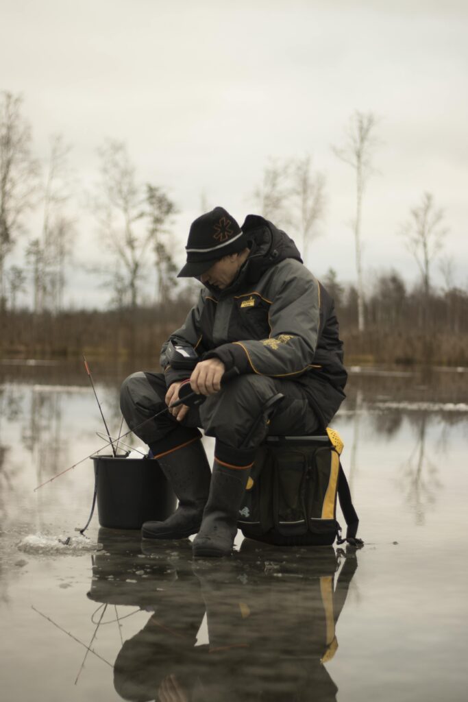 man ice fishing with rubber boots