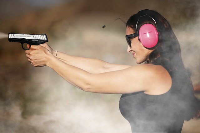 woman shooting handgun at range with ear muffs