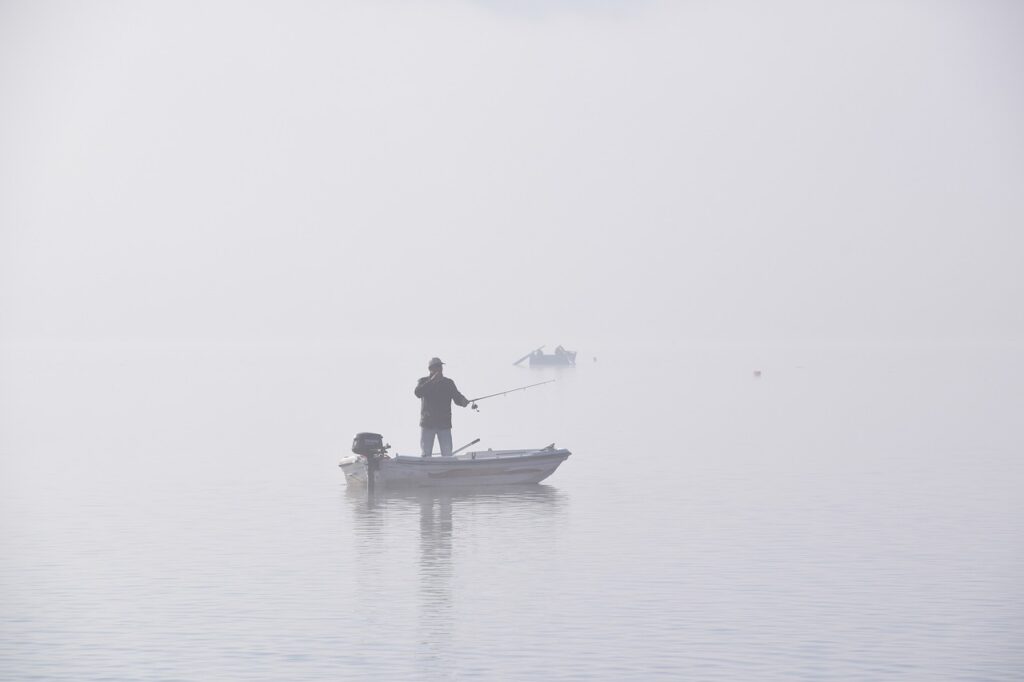 man fishing from motor boat in the fog