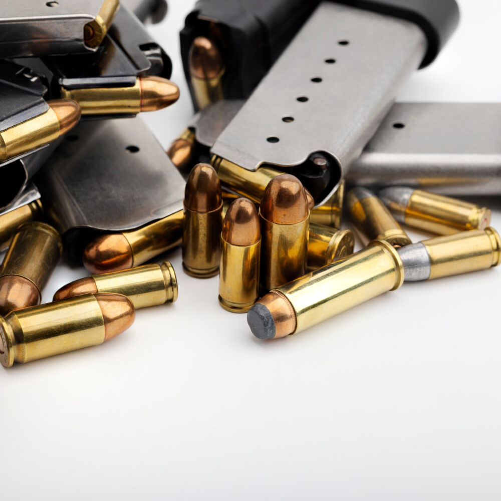 Pile of gun magazines and bullets on white background