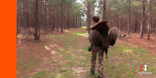 kid carrying turkey out of the woods after hunting