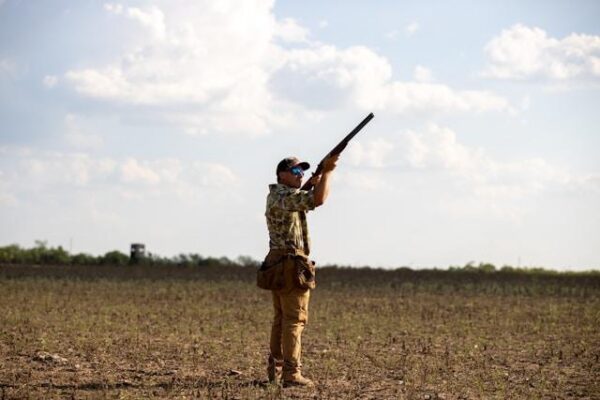 man shooting shotgun in field