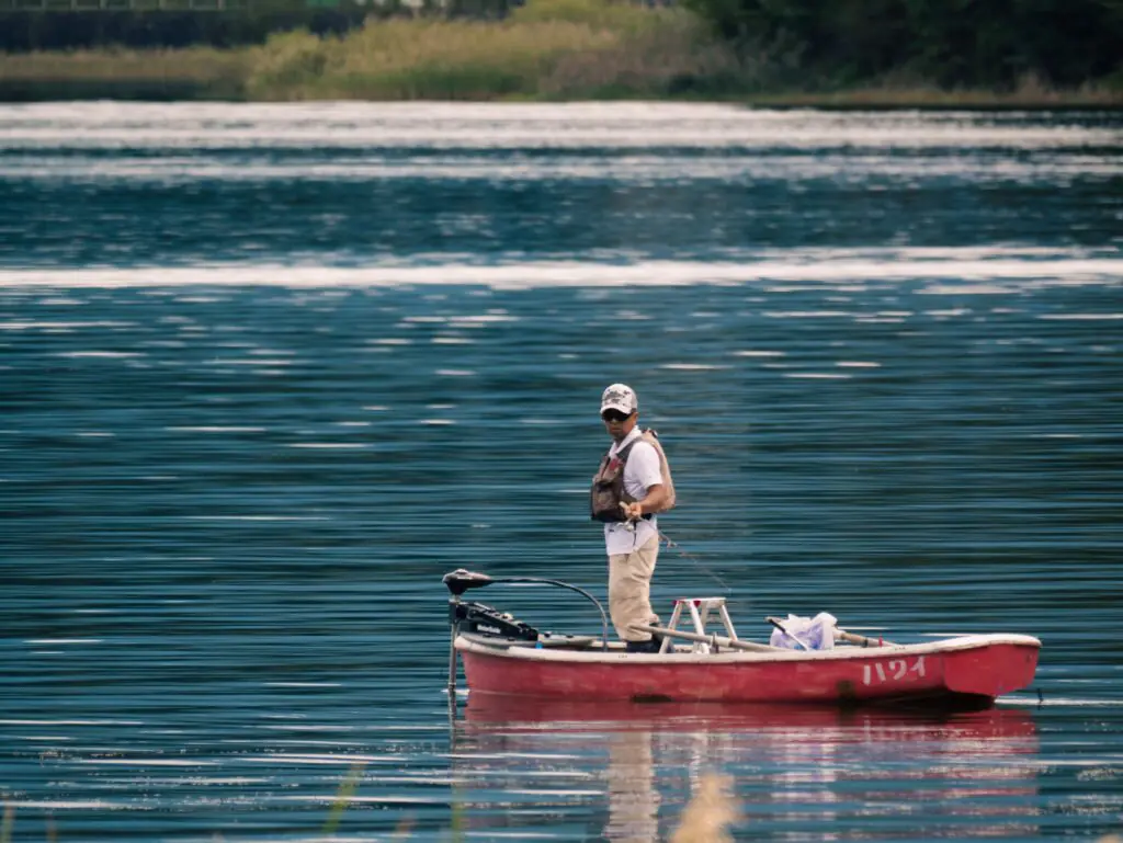 man fishing from red boat with trolling motor