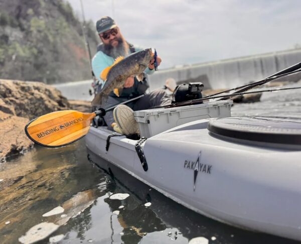 man holding bass while fishing in packable kayak