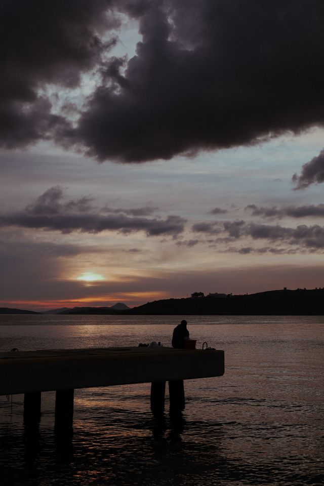 man fishing from a dock with front moving in