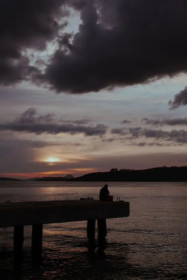 man fishing from a dock with front moving in